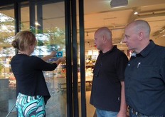 Hans en Casper kijken toe hoe Suzanne de sticker op de deur bevestigt.