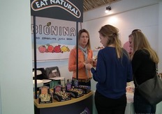 Fransje ter Doest van Lemar B.V. laat twee dames een folder zien over de mueslirepen van Eat Natural.