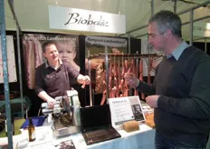 John van Lieshout laat een bezoeker proeven van biologische ham van Biobalie. Zij produceren ook de rookworst voor Labeij Food Products.