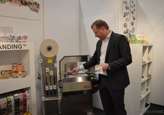 "Erik de Roos van Bandall Benelux in de stand van Max Aarts. Erik: "Ik laat hier ons 'heat sealable branding paper' zien. Deze plakken we met een 'hot melt' op waterbasis."