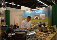 Berry Praster maakte hapjes klaar met de producten van De Lingehof. Achter hem is Marcel Jonkers (midden) druk in gesprek.