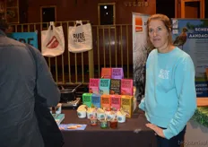 "Karlijn Audenaerde met naast haar de kleurrijke verpakkingen van het merk Rude Health. "We serveren onder meer verschillende warme dranken met de Rude Health-producten als basis)."