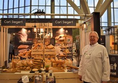 "Op de foto Nieck Welschen die ons vertelt dat Carl Siegert een nieuw brood heeft gelanceerd met de naam Oldenheimer. "Het is 100% volkoren brood met diverse zaadsoorten erin verwerkt, de broden zijn er in twee vormen: plateel en gedraaid. Oldenheimer is gebaseerd op de televisie serie de 12 van Oldenheim, welke is opgenomen in Harmelen", aldus Nieck."