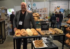 Michael Fase van Odenwald Organic Bakery. Hier kon men onder meer proeven van het bierbrood en ze toonden de 'burger buns', deze hamburgerbroodjes liggen op de tafel achter hem.