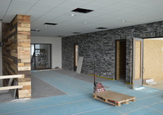 Veel van de wanden zijn voorzien van natuurlijke materialen (waaronder hout en steen). Dat is op de drie verschillende wanden op deze foto duidelijk te zien. Het hout (links) is afkomstig van een industrieterrein in Luik.