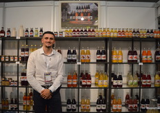 Azem Sylejmani met achter hem kasten vol sappen van de Dutch Cranberry Group.