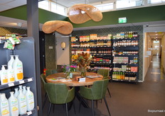 Achterin de supermarkt is een gezellige hoek gecreëerd waar klanten een kopje koffie kunnen drinken. De glazen deur geeft toegang tot het gezondheidscentrum.